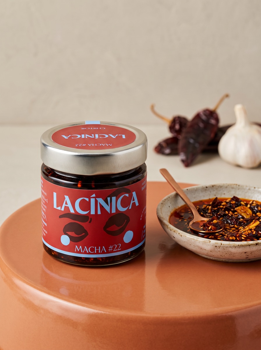 Bote de Macha #22 junto a un bol con la salsa, chiles secos y ajo